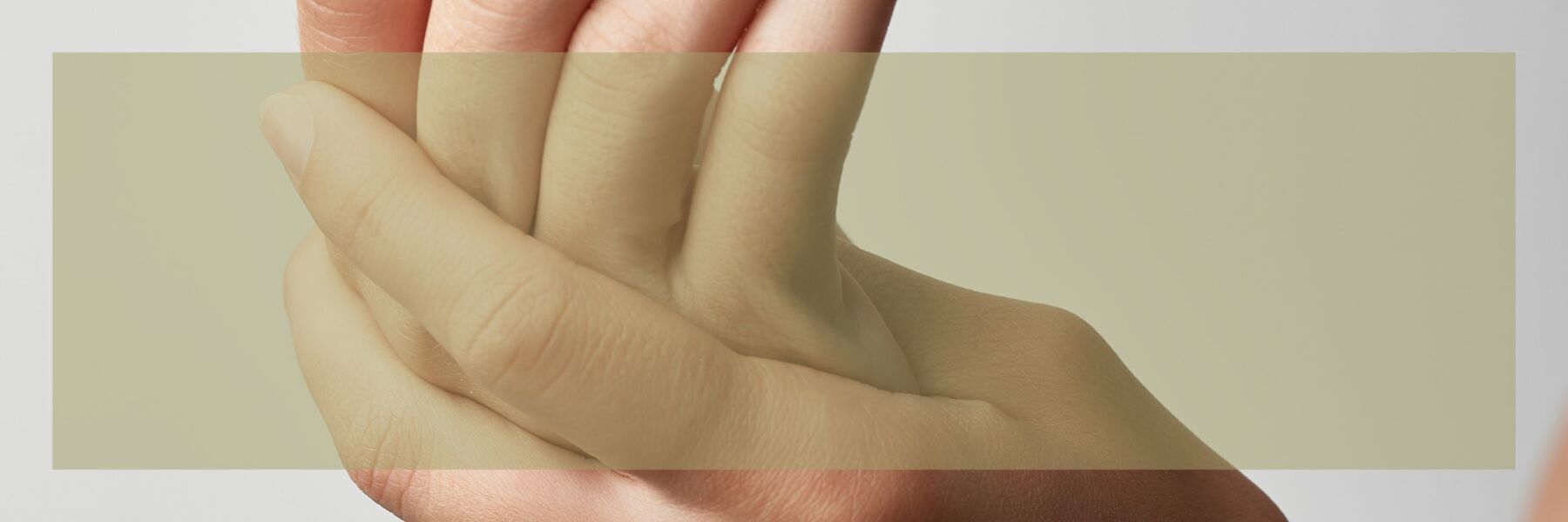 Frau hält sich ihre Hand. Symbolisiert Schmerzen.